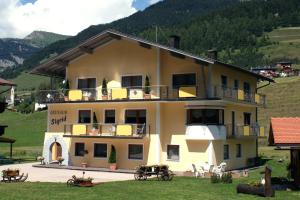 a large yellow building with tables and chairs in front of it at Gästeheim Sigrid in Nauders