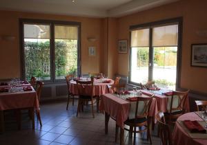 Un comedor con mesas y sillas y ventanas. en Relais Touraine Sologne, en Noyers-sur-Cher