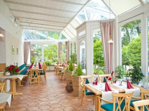 a restaurant with tables and chairs in a conservatory at Flair Landhotel Strengliner Mühle in Pronstorf