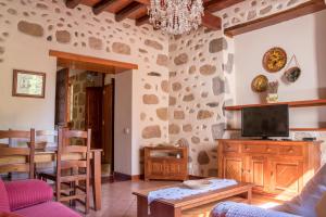 een woonkamer met een tv en een stenen muur bij Casa Rural Doña Margarita in Teror