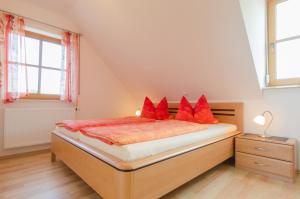 Un dormitorio con una cama con almohadas rojas. en Panorama Ferienwohnungen Thiem en Waischenfeld