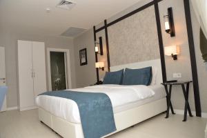 a bedroom with a large white bed with blue pillows at Gardenya Suite Hotel in Trabzon +39 photos