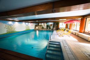 a large swimming pool with chairs and a table at Land-gut-Hotel Landgasthof Zum Schildhauer in Halfing