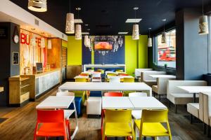 a restaurant with white tables and colorful chairs at ibis budget London Hounslow in Hounslow