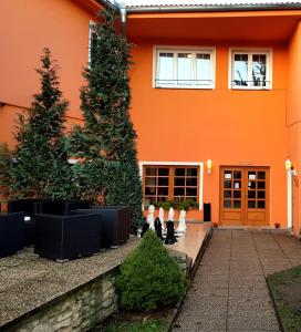 una casa naranja con un árbol delante de ella en Hotel Swami en Mělník