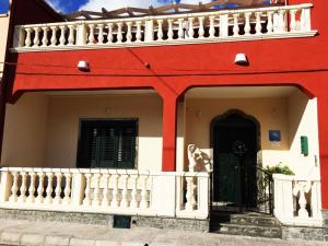 uma casa vermelha e branca com uma varanda branca em B&B Casa Alba Salentina em Porto Cesareo