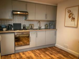 a kitchen with white cabinets and a wooden floor at Flat 4, York Terrace in Norwich