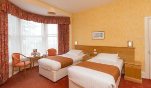 a hotel room with two beds and a desk at Lauriston Hotel in Weston-super-Mare