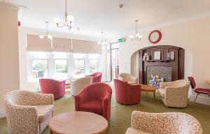 a waiting room with chairs and tables and a clock at Lauriston Hotel in Weston-super-Mare