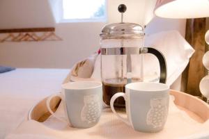 two cups of coffee sitting on a table with a coffee pot at Castle Cottage Orford in Orford
