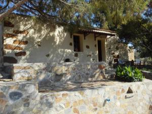 a house with a stone wall and a tree at Trouli House in Stalos
