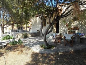 a patio with a table and chairs under a tree at Trouli House in Stalos