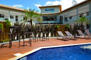 a hotel with chairs and a pool and a building at Hotel Bertell Inn in Penedo