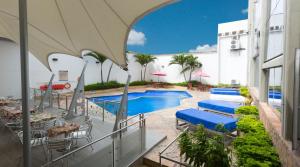 an outdoor patio with a pool and tables and chairs at Atlantis Plaza Hotel Cúcuta in Cúcuta
