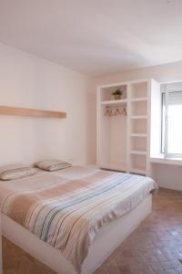 a white bedroom with a large bed and a window at BoardXhouse in Imsouane