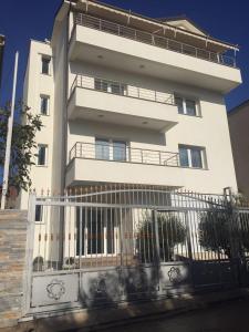a white building with a fence in front of it at Brilant Apartament in Tirana