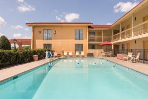 a swimming pool at a hotel with tables and chairs at Baymont by Wyndham Greenville Woodruff Rd in Greenville