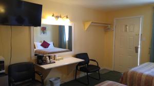Cette chambre comprend un lit, un bureau et des chaises. dans l'établissement Robber's Roost Motel, à New Hazelton