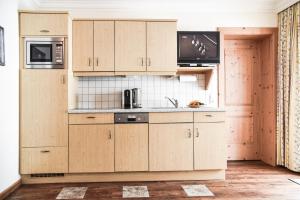 a kitchen with wooden cabinets and a sink at Appartementhaus Unterkofler in Grossarl