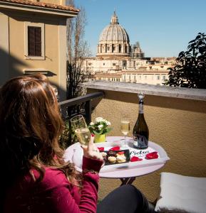 una mujer sentada en una mesa con una copa de vino en San Pietro Panoramic View, en Roma