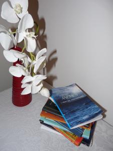 a stack of books next to a vase with flowers at Ánemos b&b in Termoli