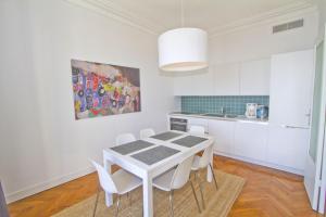 - une cuisine blanche avec une table et des chaises blanches dans l'établissement PROMENADE HOLIDAY - SOLEMAR PROMENADE, à Nice