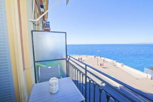 a table on a balcony with a view of a beach at PROMENADE HOLIDAY - ROCAMARE PROMENADE in Nice