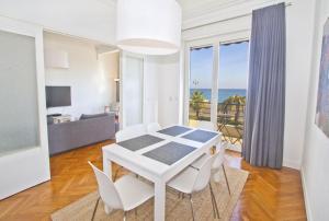 une salle à manger blanche avec une table et des chaises et l'océan dans l'établissement PROMENADE HOLIDAY - SOLEMAR PROMENADE, à Nice