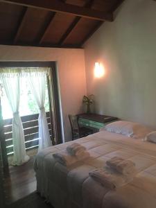 um quarto com uma cama, uma janela e uma secretária em Casa pé na areia - Praia do Felix em Ubatuba