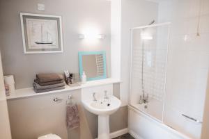 a white bathroom with a sink and a shower at Comfortable Belfast city centre apartment in Belfast