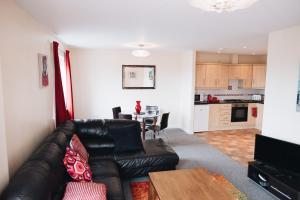a living room with a leather couch and a table at Comfortable Belfast city centre apartment in Belfast