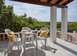 una mesa blanca y 4 sillas en un patio en Viviendas Los Olivos - Formentera Break, en Playa de Migjorn