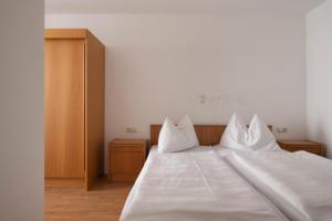 a bedroom with a white bed with two pillows at Appartements Christophorus in Bad Hofgastein