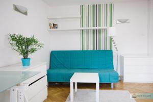 Sofá azul en una habitación blanca con mesa en Warsaw Concierge Zlote Tarasy Apartment en Varsovia