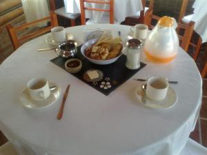 una mesa blanca con tazas y un plato de comida en Las Esmeraldas en Nono