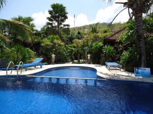 een zwembad met twee blauwe banken in een resort bij Three Brothers Bobby's Villas in Amed