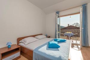 a bedroom with a bed with blue pillows and a balcony at Apartments Ivana-Gustirna in Gustirna