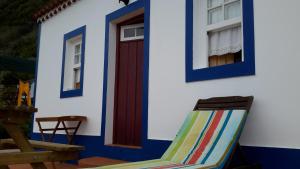 a chair in front of a house with a red door at Casa da Fajãzinha in Vila do Porto