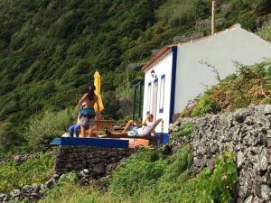 a woman in a bikini standing outside a building with a person at Casa da Fajãzinha in Vila do Porto
