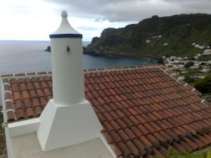 a lighthouse sitting on top of a roof next to the ocean at Casa da Fajãzinha in Vila do Porto