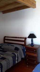 a bedroom with a bed and a lamp on a dresser at Casa da Fajãzinha in Vila do Porto
