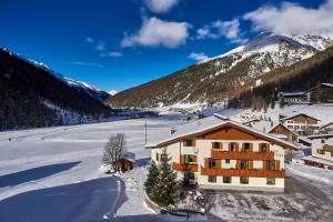 a building in the snow in front of a mountain at Garni Appartements Arnika in Solda