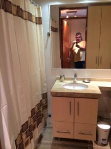 a man taking a picture of a bathroom with a sink at Apart Magallanes in Santiago