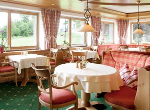 a restaurant with white tables and chairs and windows at Hotel Rössle in Bernau im Schwarzwald
