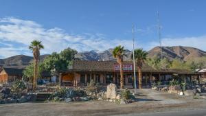 um edifício com palmeiras e montanhas ao fundo em Panamint Springs Motel & Tents em Panamint Springs