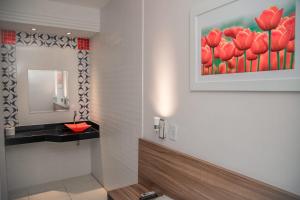 um banheiro com uma pintura de tulipas vermelhas em Hotel Astoria em Palmas mais 28 fotografias
