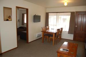 a living room with a table and chairs and a room with a couch at Carisbrook Motel in Dunedin