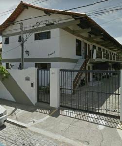 a white house with a fence in front of it at Apartamento em Cabo Frio in Cabo Frio