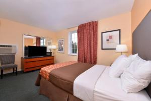 a hotel room with a bed and a flat screen tv at Media Inn & Suites in Media