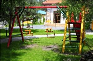 un parque con columpios en el césped en Dom Bankietowy Arkadia, en Sochaczew